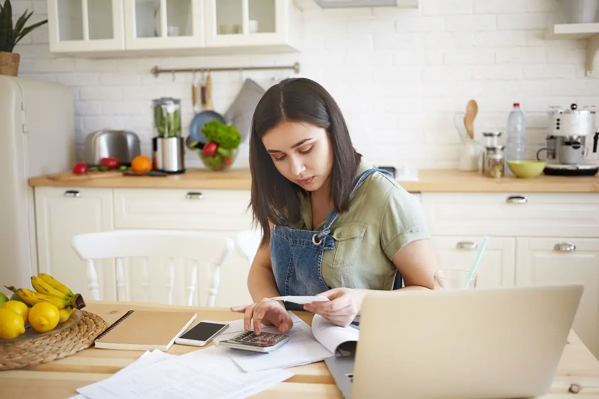 Mulher revisando contas e boletos em casa para reduzir gastos fixos e economizar mais dinheiro todo mês.